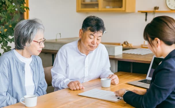 話をしている年配の夫婦と女性社員